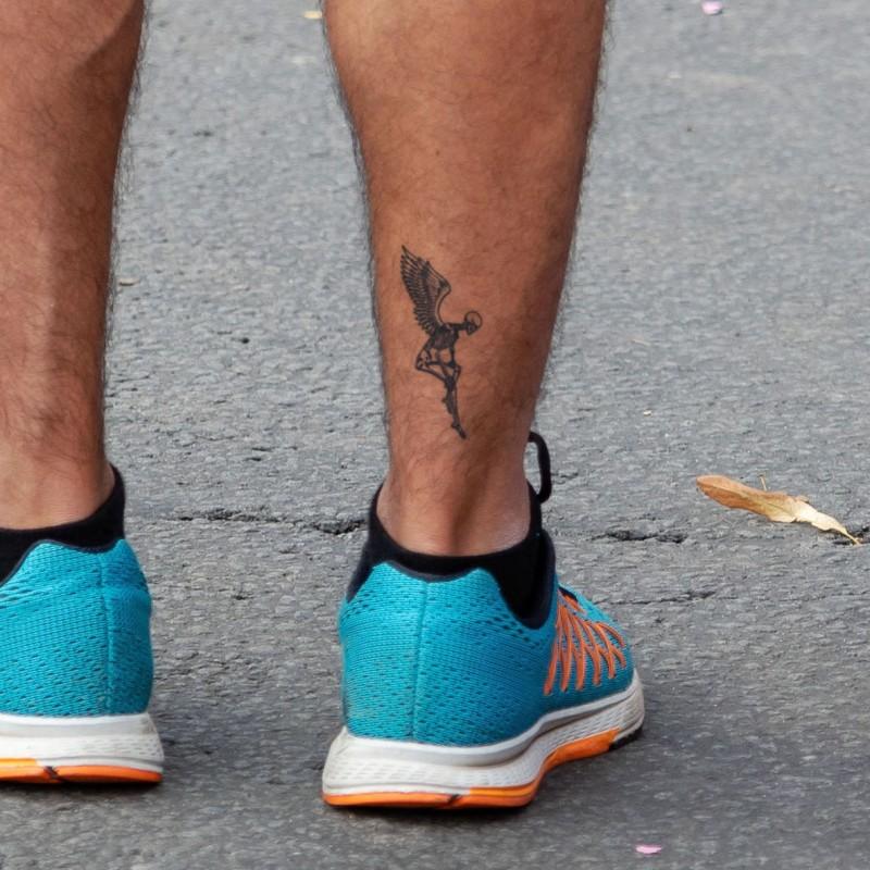 Micro-realistic wing tattoo on the ankle.
